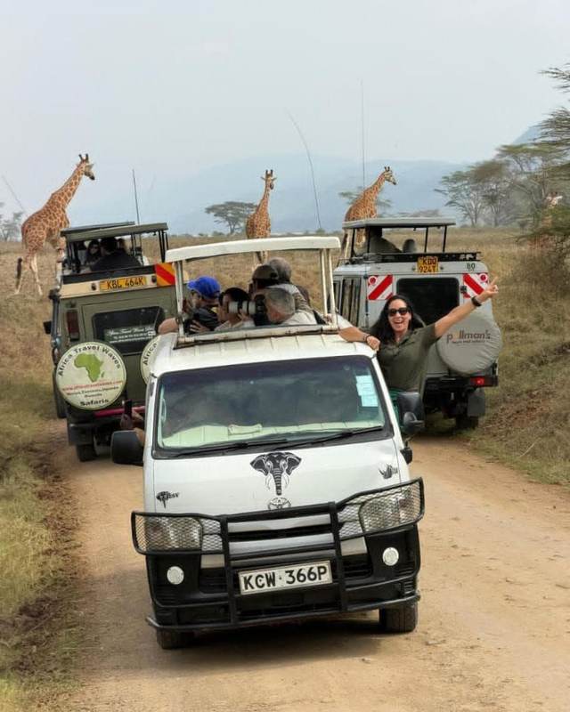 ELMAG SAFARIS pop-top safari van on a Kenyan game drive with giraffes beside the track